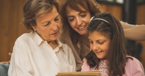 Abuela, hija y nieta mirando un libro