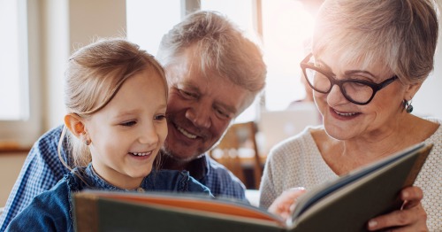 Imagen de dos abuelos con su nieta leyendo un libro