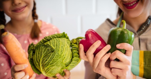 Madre e hija sosteniendo verduras que ayudan a retrasar el envejecimiento celular