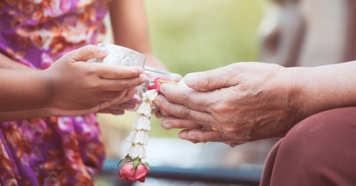 Manos de nieta ofreciendo flores a su abuela