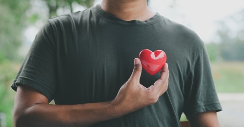 Hombre sujetando sobre el pecho una figura de un corazón