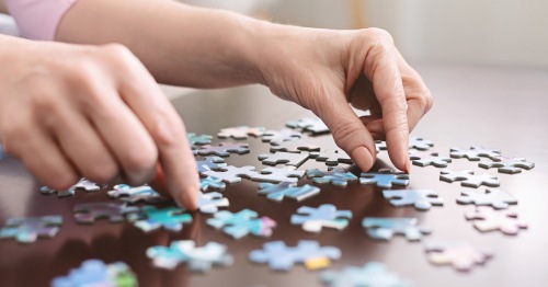 Primer plano de unas manos de persona mayor haciendo un puzle para combatir la pérdida de memoria