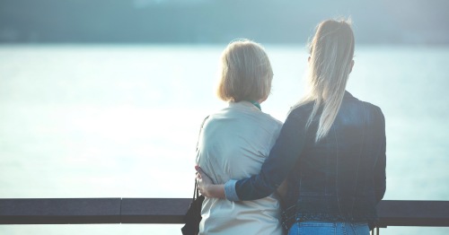 Madre e hija de espaldas mirando al mar