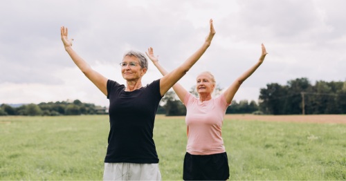 Dos mujeres mayores de 60 años haciendo estiramientos al aire libre
