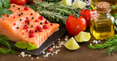 Imagen de varios alimentos con vitaminas para mayores de 60 años, como el salmón o el aceite de oliva
